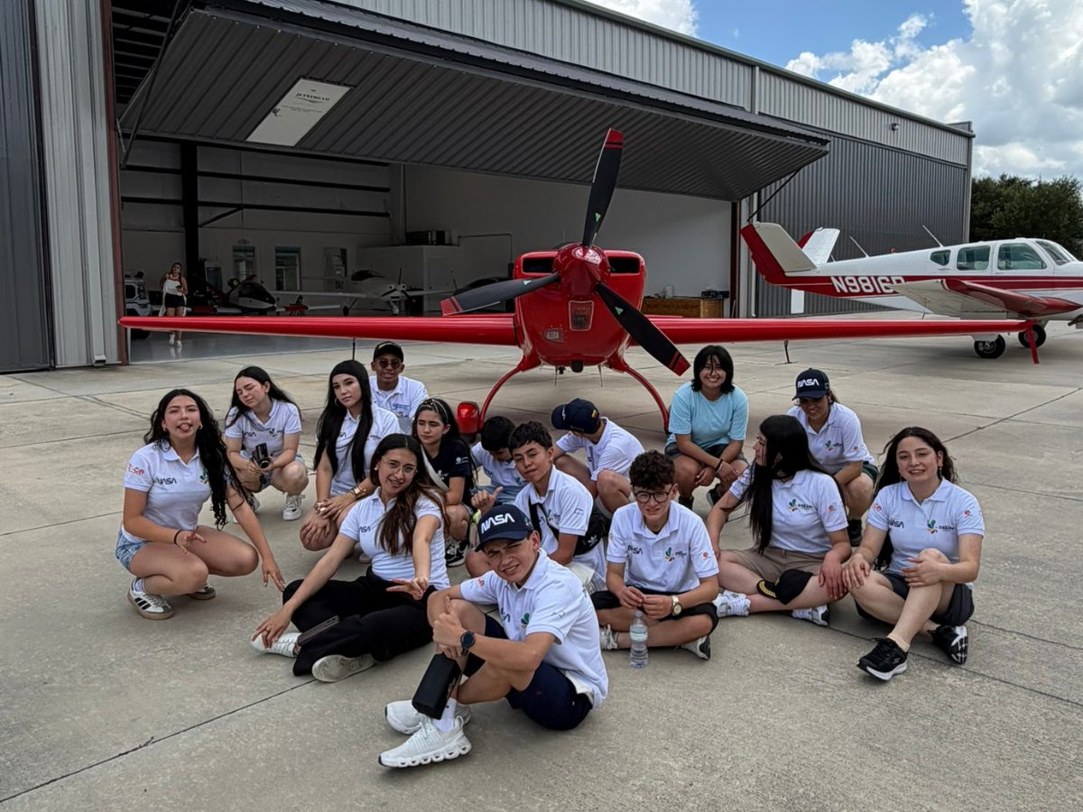 La tripulación Dream STEAM sentada frente a una avioneta roja en el hangar