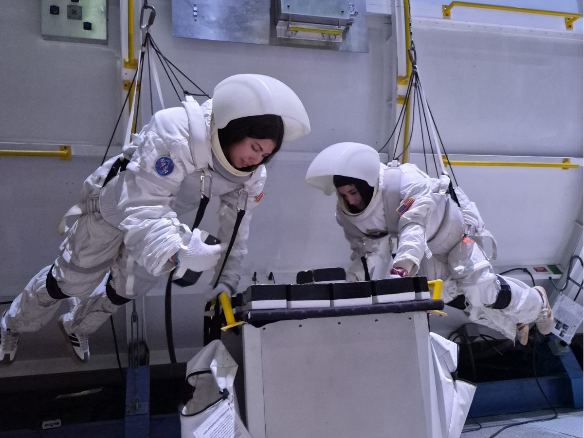 Dos tripulantes con traje espacial entrenando una caminata espacial en microgravedad simulada